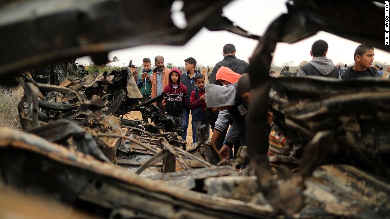 People gather Monday around a vehicle destroyed in an Israeli air strike in Gaza.