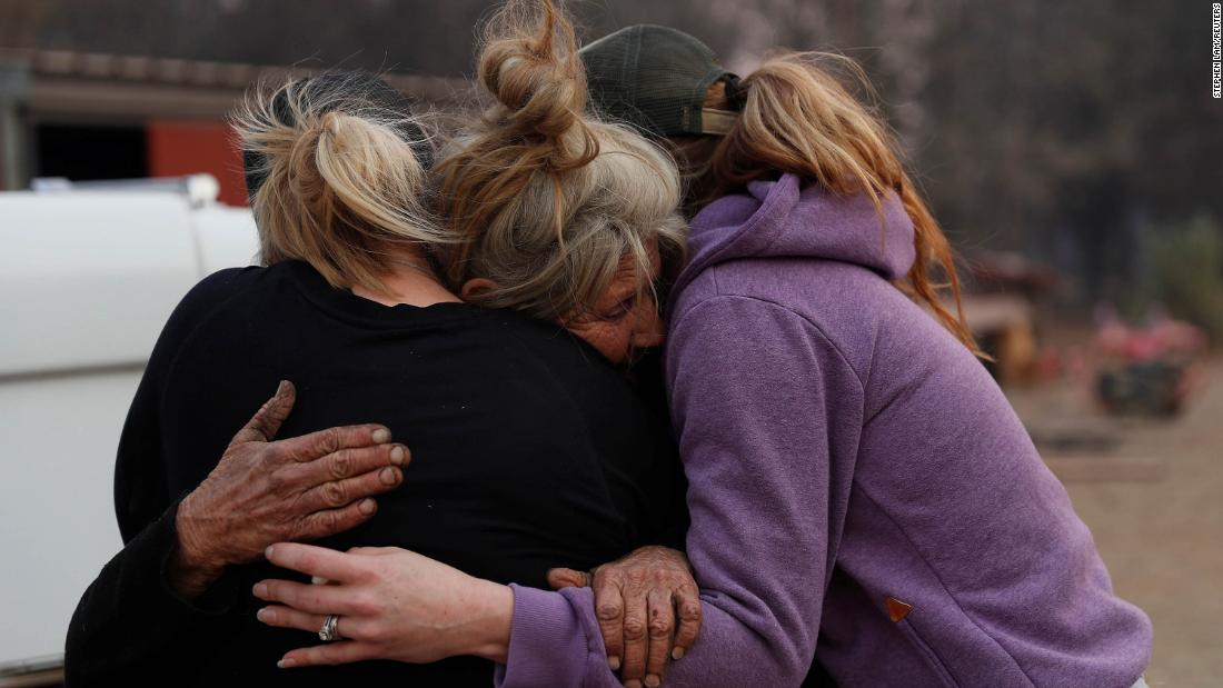 Cathy Fallon, who stayed behind in Paradise to tend to her horses during the Camp Fire, embraces Shawna De Long, left, and April Smith, right, who brought supplies for the horses.