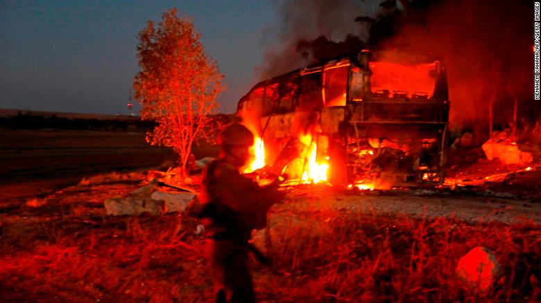 Israeli security forces and firefighters gather near the bus hit by fire from Gaza.