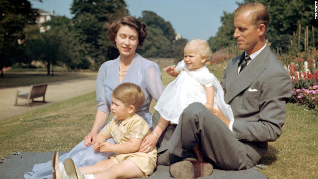 Princess Elizabeth and her husband, Prince Philip, sit on a lawn with their children Prince Charles and Princess Anne in August 1951.