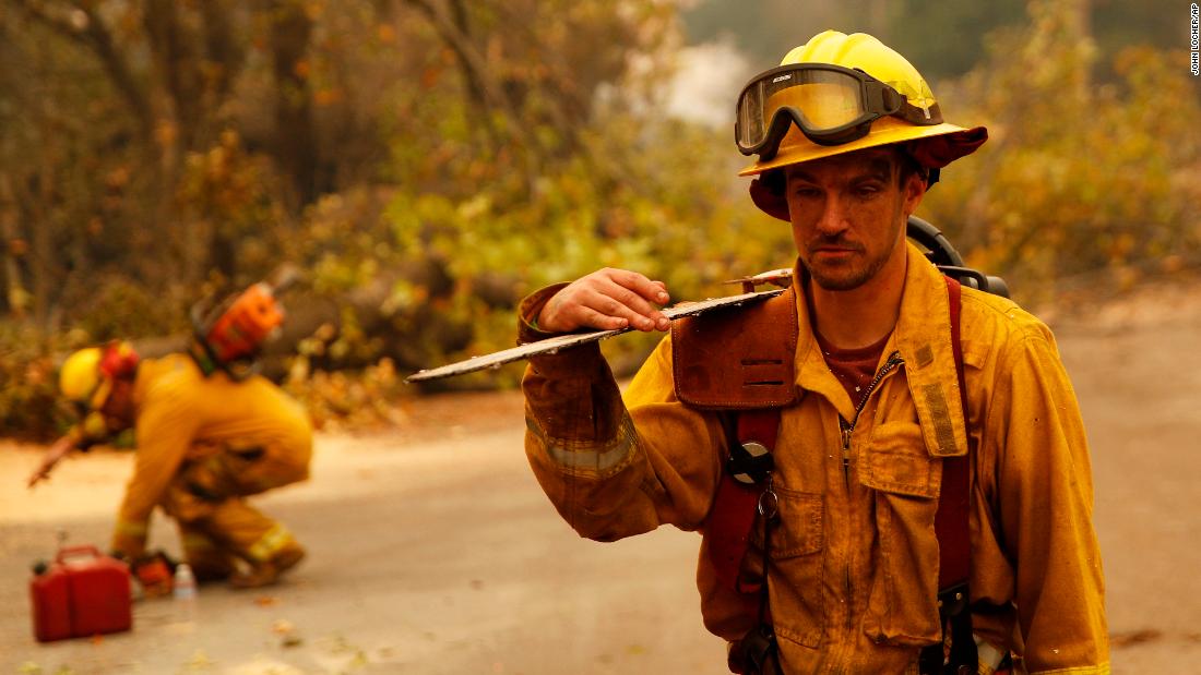 Shawn Slack carries a chainsaw on November 12 after trees burned in Paradise.