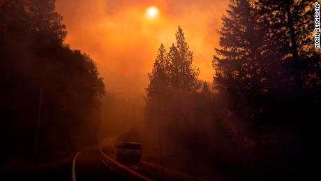 A vehicle drives through smoke from a wildfire near Pulga Sunday.