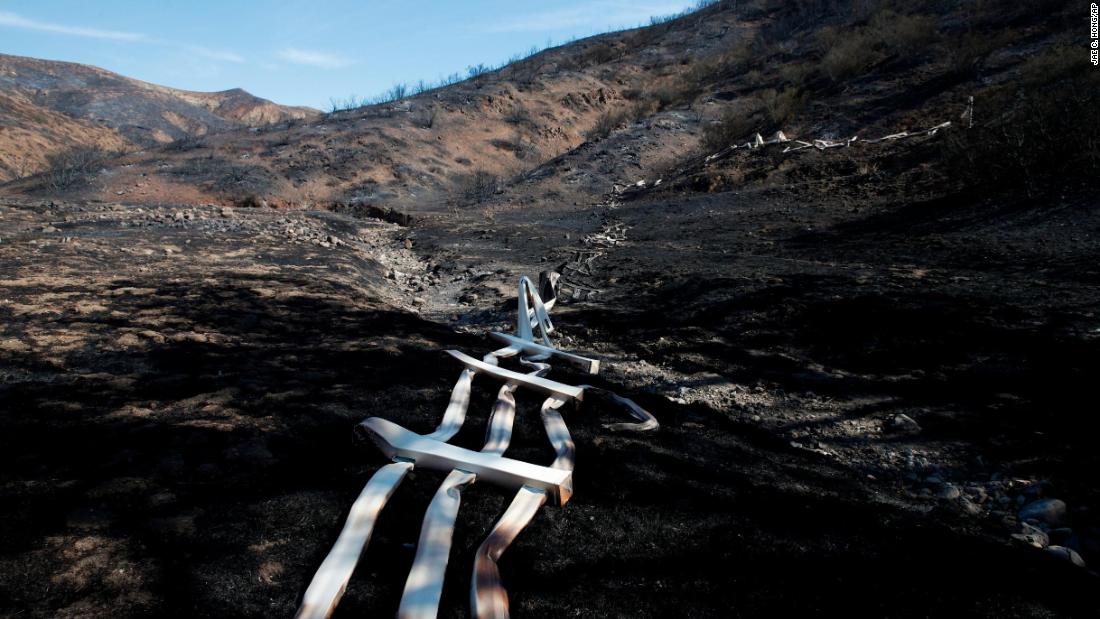 A melted fence runs along a hillside as firefighters battle the Woolsey Fire in Agoura Hills on November 13. 