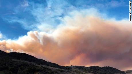 An airplane flies over a large wildfire plume from a recent flareup of the Woolsey Fire near Lake Sherwood, Calif., Tuesday, Nov. 13, 2018. Forecasters had warned of continuing fire danger in Southern California due to persistent Santa Ana winds, the withering, dry gusts that sweep out of the interior toward the coast, pushing back moist ocean breezes.  (AP Photo/Amanda Myers)