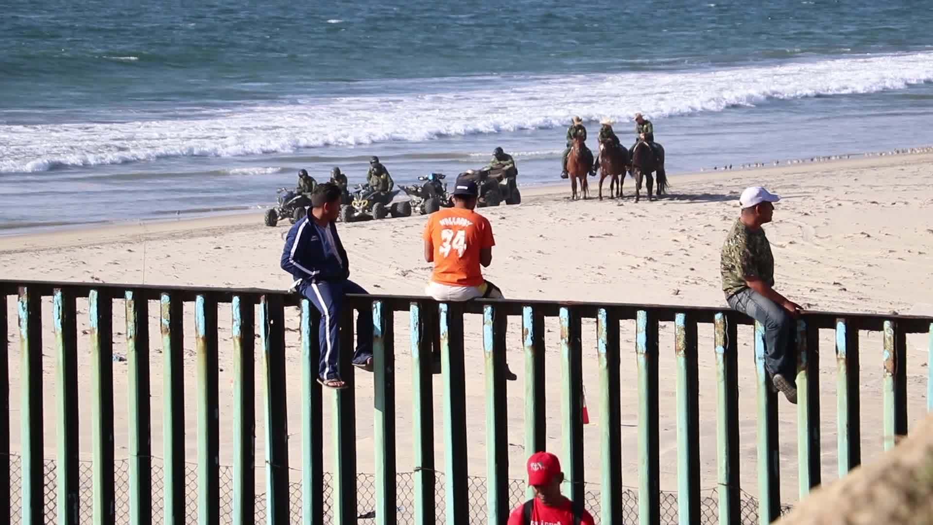 Migrantes de la caravana trepan valla fronteriza entre Tijuana y