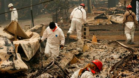 Search and rescue workers search for human remains at a trailer park burned out from the Camp Fire.