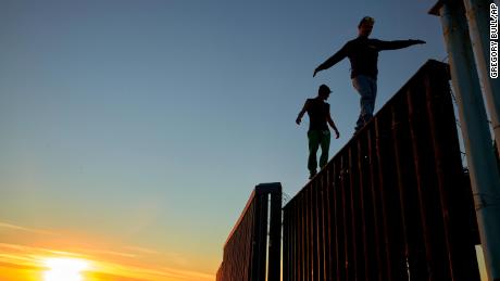 Two Central American migrants walk along the top of the border structure separating Mexico and the United States on Wednesday in Tijuana.