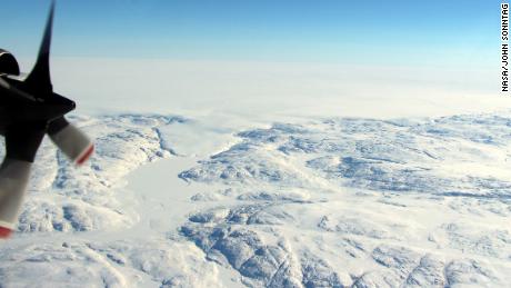 The Hiawatha impact crater is covered by the Greenland Ice Sheet, which flows just beyond the crater rim, forming a semi-circular edge. Part of this edge, seen in the top of the photograph, and a tongue of ice that breaches the crater&#39;s rim are shown in this photo taken during a NASA flight in April.