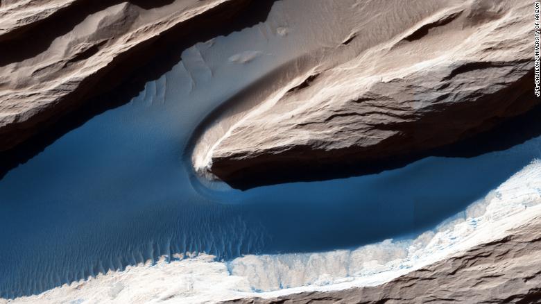 Although Mars isn&#39;t geologically active like Earth, surface features have been heavily shaped by wind. Wind-carved features such as these, called yardangs, are common on the Red Planet. On the sand, the wind forms ripples and small dunes. In Mars&#39; thin atmosphere, light is not scattered much, so the shadows cast by the yardangs are sharp and dark.