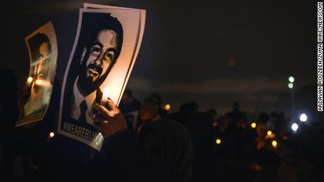 Supporters hold posters of Bijan at a vigil.