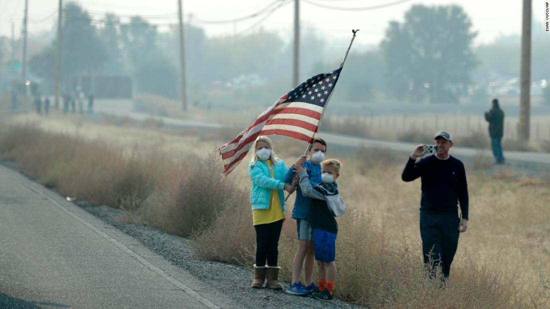 A group of children hold an American flag as the motorcade of President Donald Trump drives through Chico, California, on November 17.