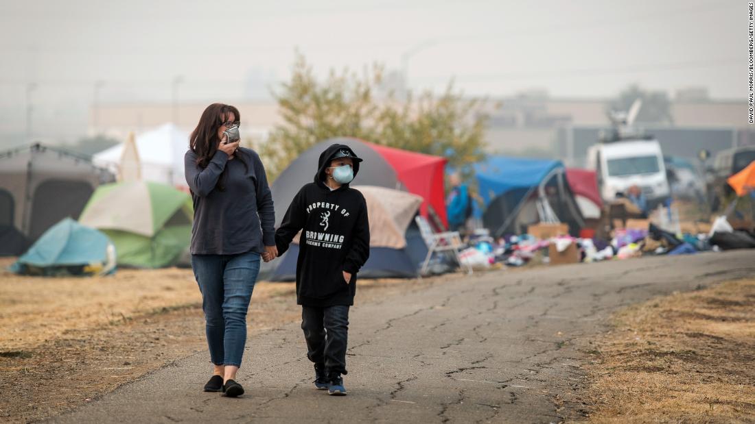 Evacuees wear disposable face masks as they walk through the tent city on November 15.