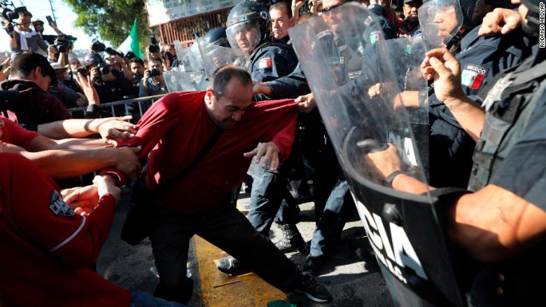 Demonstrators clash with police outside a migrant shelter as they protest the presence of thousands of Central American migrants in Tijuana on Sunday.