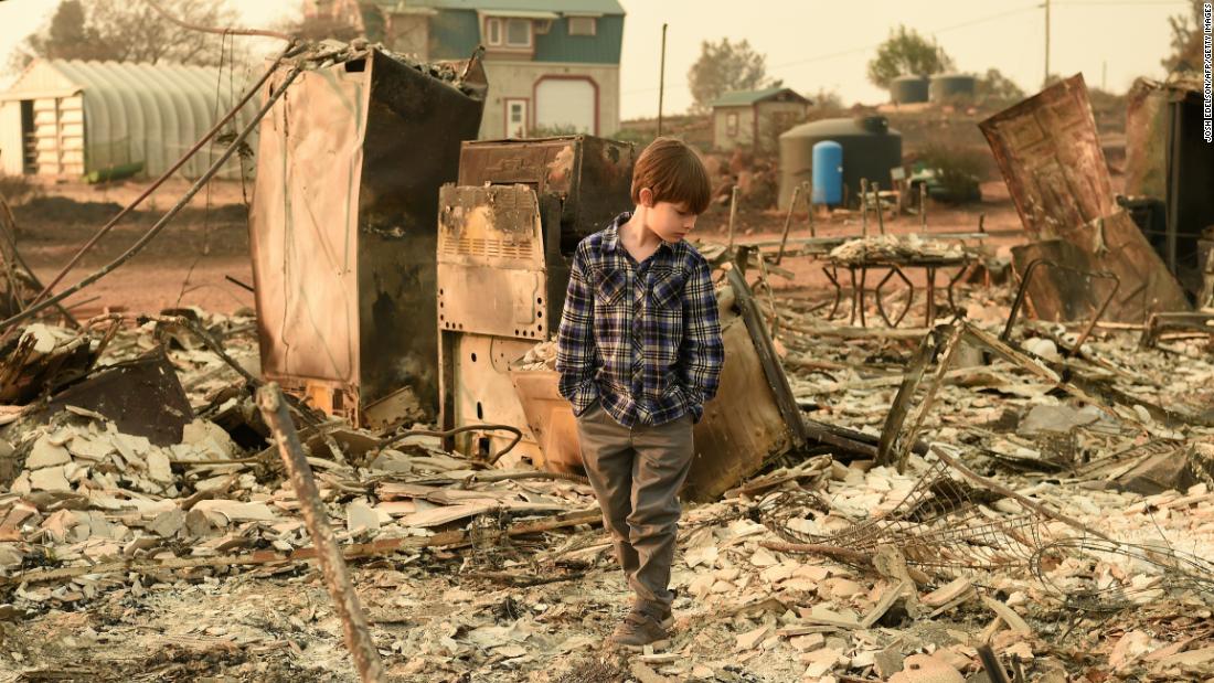 Jacob Saylors, 11, walks through the burned remains of his home in Paradise, California, on Sunday, November 18. His family lost a home in the same spot to a fire 10 years earlier. 