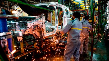 Factory employees work on a car assembly line at Renault-Nissan.