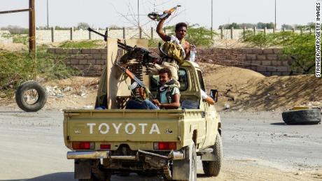 Pro-government forces cheer in the back of a pickup mounted with a machine gun outside Hodeidah.