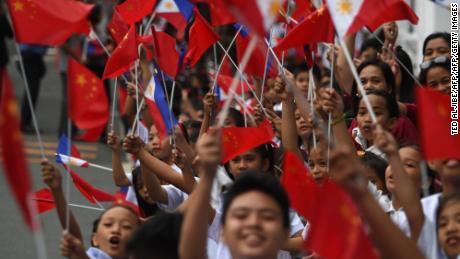 Schoolchildren wave the  flags of the Philippines and China as they line up November 20 along the route of China's President Xi Jinping's motorcade in Manila.