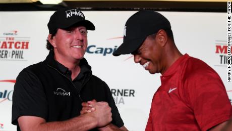 Phil Mickelson and Tiger Woods shake hands during a press conference.