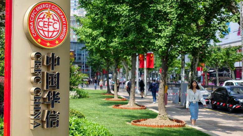 Pedestrians walk past a signboard of China CEFC Energy in Shanghai, China, in May 2018.
