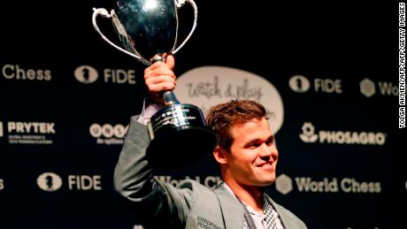 Carlsen poses with the FIDE world chess championship trophy 