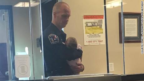 Officer Robert Lofgran cuddled an infant and watched two more children as their mother filled out paperwork for a domestic violence report.