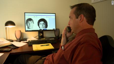 A computer displays facial composites for two unidentified victims as Moran works the phone in the Gacy cold cases.