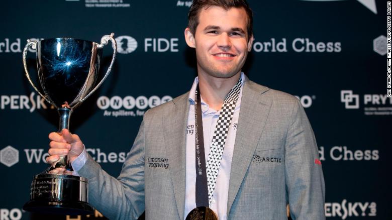 Carlsen holds his trophy up after beating Fabiano Caruana to regain his World Chess Championship title on November 28, 2018 in London.