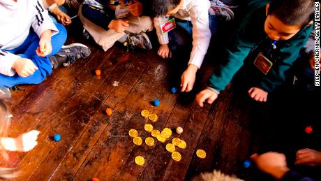 NEW YORK - 4 DICEMBRE: Gli studenti della seconda elementare giocano con i dreidel e le monete d'oro di cioccolato dopo aver acceso la menorah il 4 dicembre 2007 alla sinagoga di Eldridge St. La classe era lì per imparare Hannukah e anche sulla sinagoga appena restaurata che originariamente aprì le sue porte nel 1887. (Foto di Stephen Chernin/Getty Images)