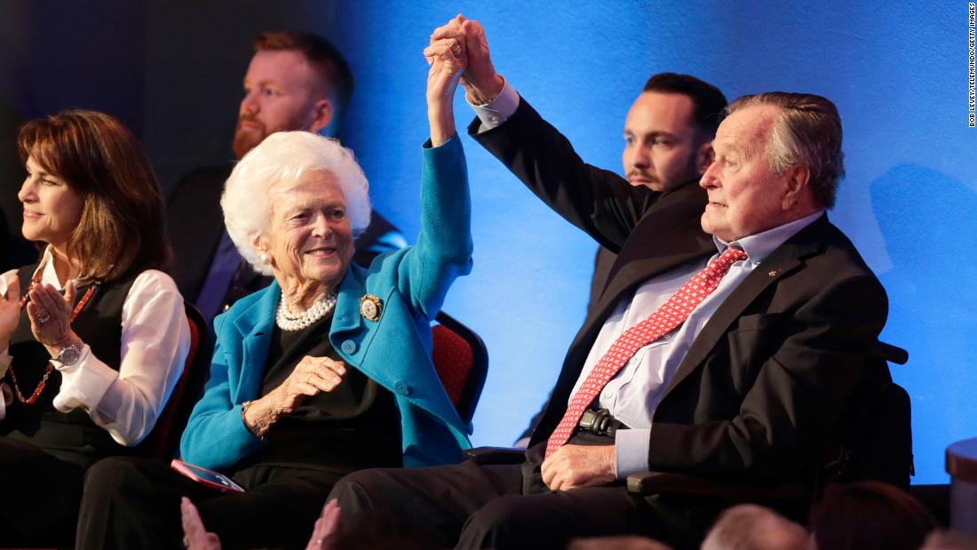 Bush holds up his wife&#39;s hand at a Republican presidential debate in 2016. One of their sons, former Florida Gov. Jeb Bush, was among the candidates in the debate.