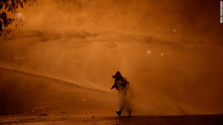 A demonstrator leaves as water cannons evacuate the Place de l&#39;Etoile on  Saturday, December 1, in Paris.