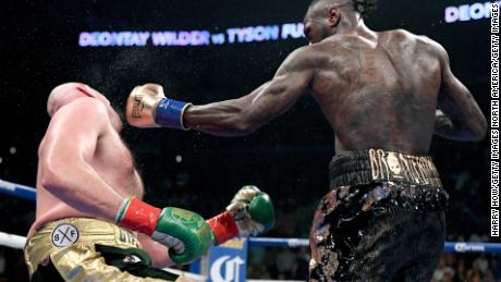 Deontay Wilder knocks Tyson Fury down during the 12th round to earn the draw and retain his belt. 