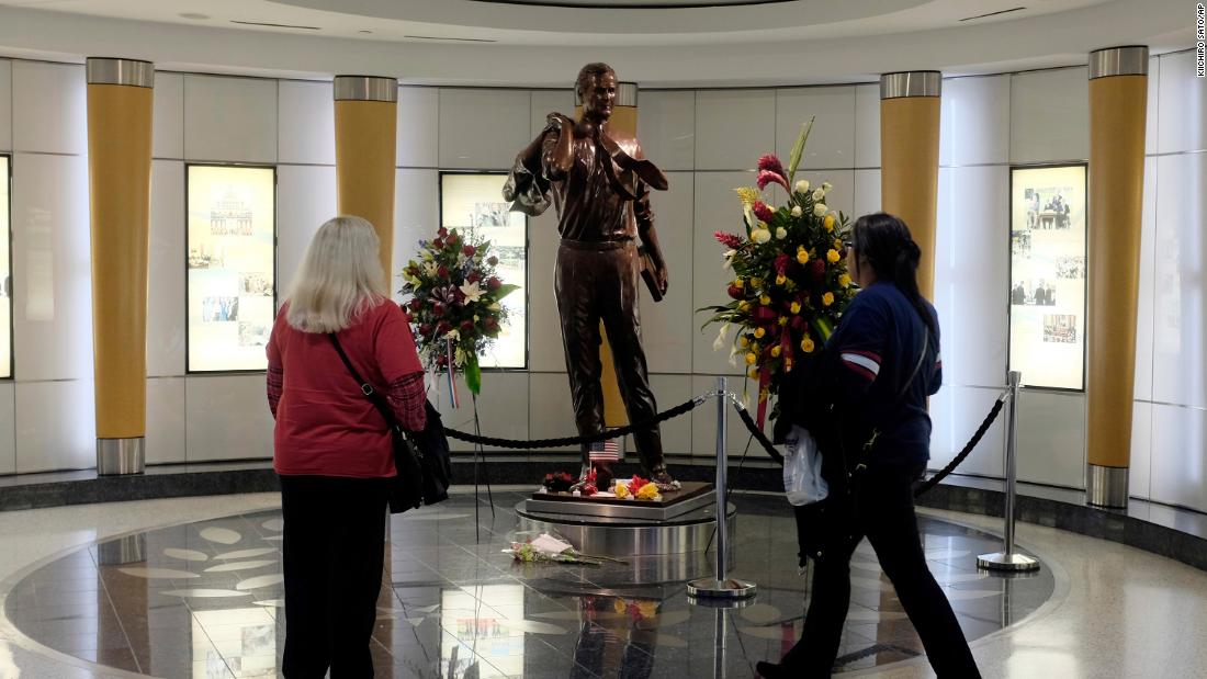 Travelers stop at a statue of the former President as they arrive at Houston&#39;s George Bush Intercontinental Airport on Sunday, December 2.
