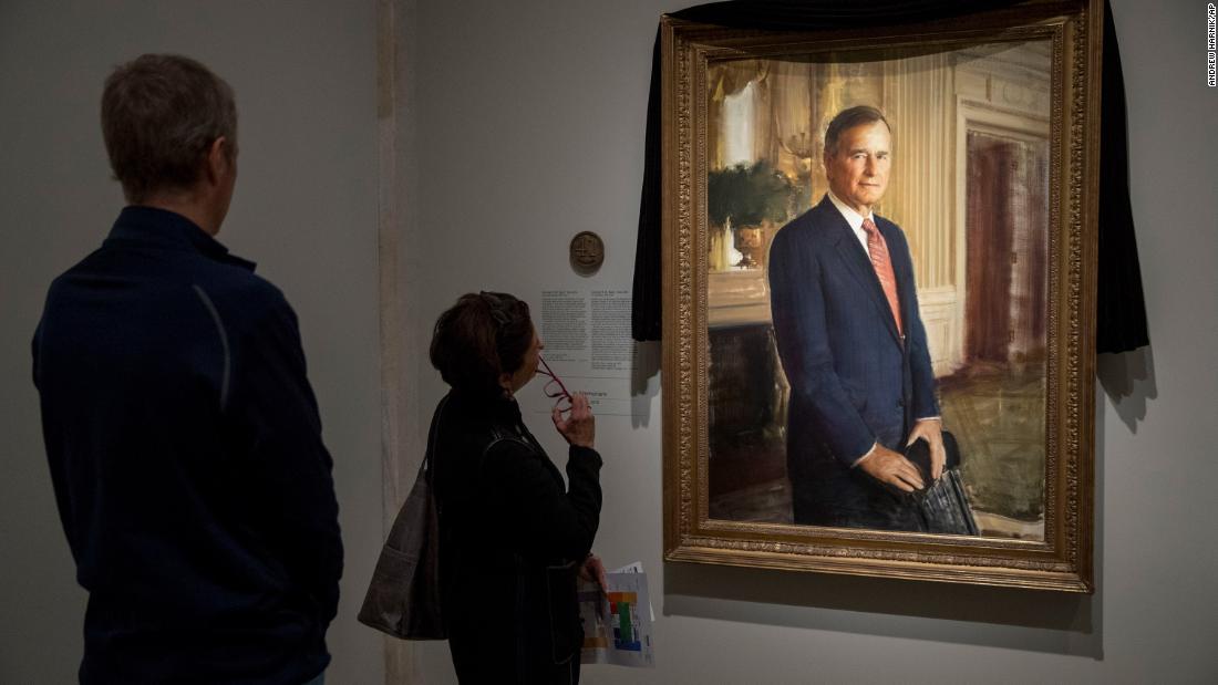 People look at Bush&#39;s official portrait, which was draped in black cloth at the National Portrait Gallery in Washington.