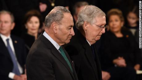 Senate Majority Leader Mitch McConnell, at right, and US Senate Minority Leader Chuck Schumer, at left, pay their respects during the service for former US President George H.W. Bush as he lies in state at the US Capitol during a ceremony in Washington, DC. (Photo by Brendan SMIALOWSKI / AFP)