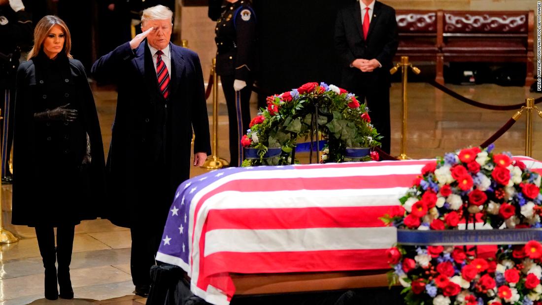 President Donald Trump salutes as he and first lady Melania Trump pay their respects to Bush on December 3. 