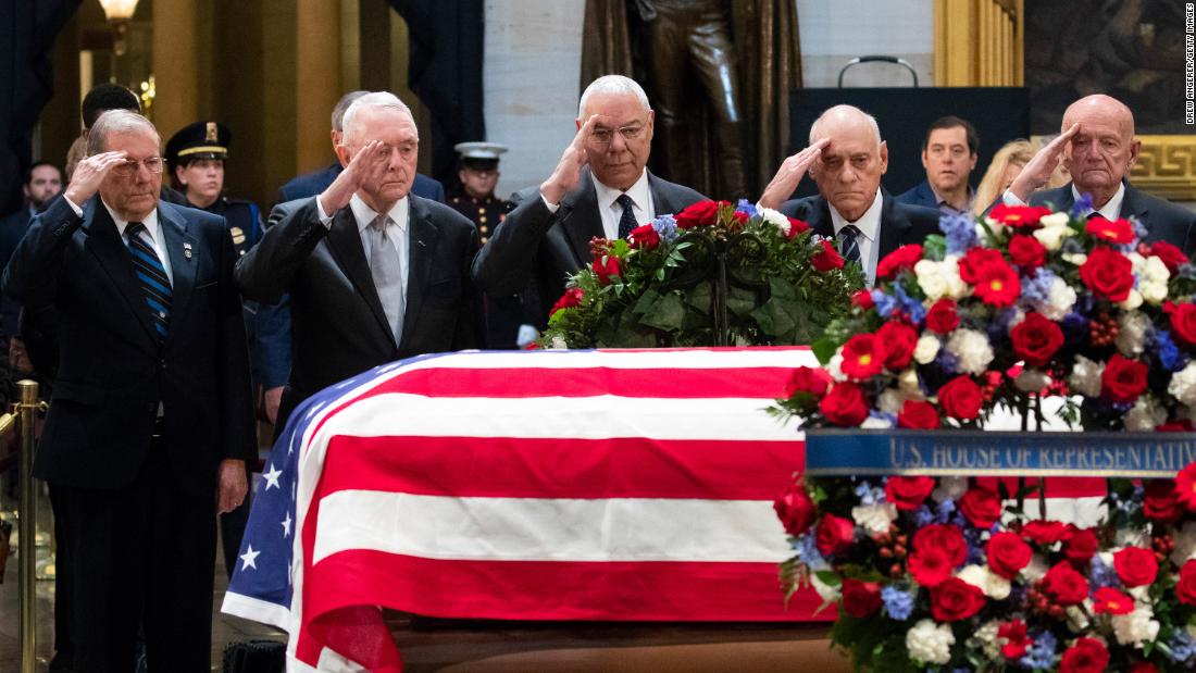 Former Secretary of State Colin Powell, who under Bush was chairman of the Joint Chiefs of Staff, salutes Bush at center along with other former military officials.