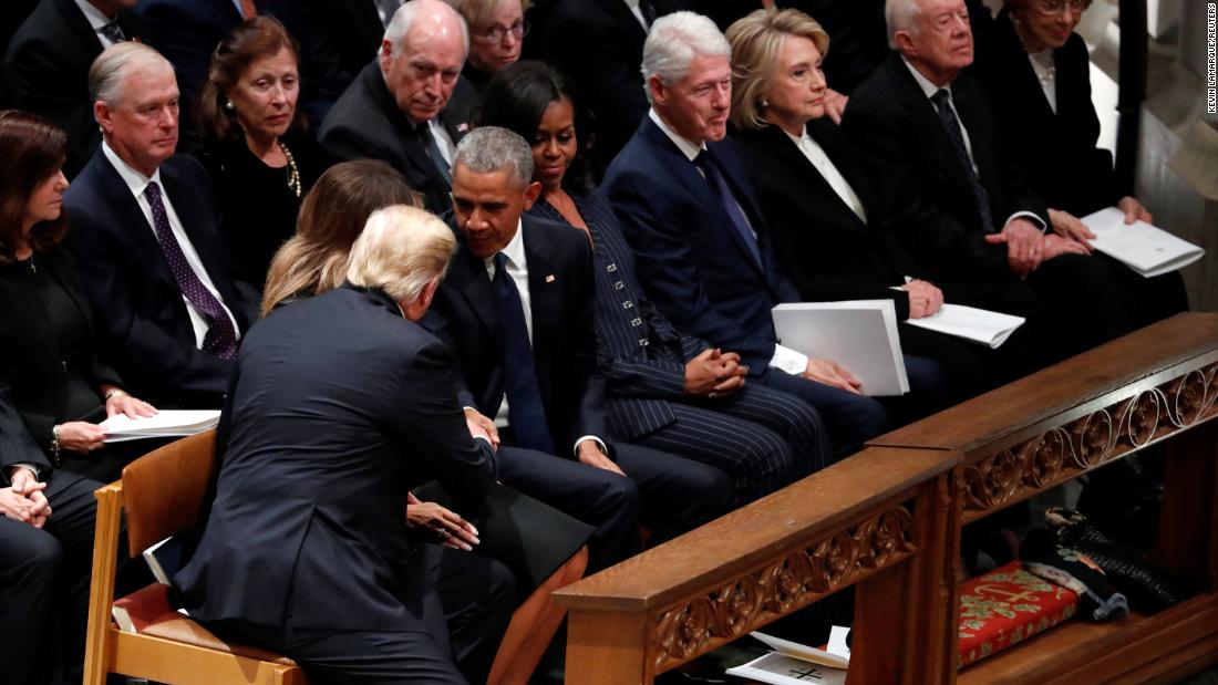 President Donald Trump reaches over to shake hands with former President Barack Obama as he and his wife, Melania, take a seat in the first row along with former first lady Michelle Obama, former President Bill Clinton, former first lady Hillary Clinton, former President Jimmy Carter and former first lady Rosalynn Carter.
