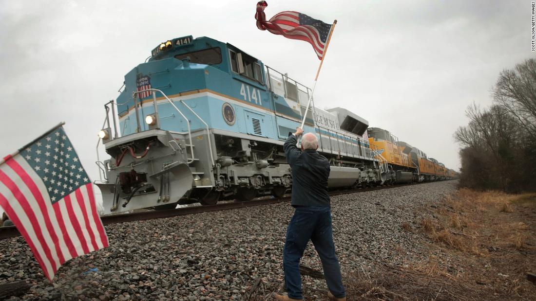 Peter Olyniec waves an American flag as George H.W. Bush&#39;s train passes near Whitehall, Texas, on Thursday, December 6. Bush&#39;s body was en route to his presidential library in College Station, Texas, where he was laid to rest.