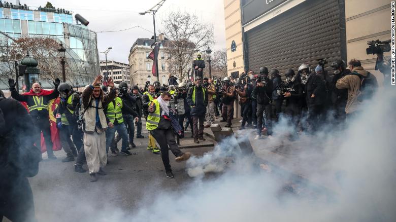 Protesters clash with riot police amid tear gas on the Champs-Elysees in Paris on December 8.