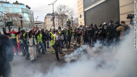 Protesters clash with riot police amid tear gas Saturday on the  Champs-Élysées in Paris.