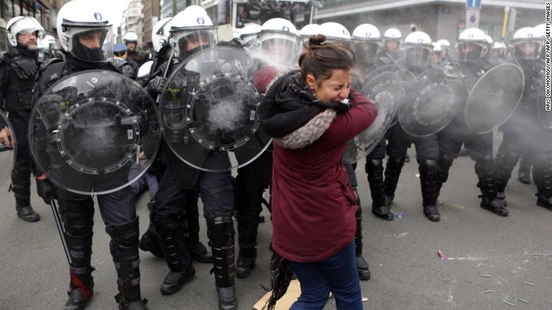Riot police forces spray tear gas at a woman during copycat demonstrations in Brussels.