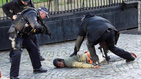 Armed police restrain a man inside the grounds of the Houses of Parliament on Tuesday.