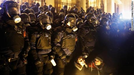 Demonstrators hold position in front of policemen wearing gas masks.