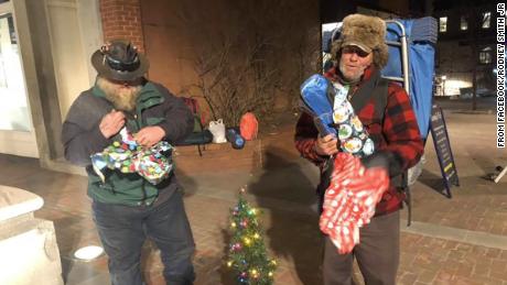 Two homeless men open presents they received from Rodney Smith Jr. 