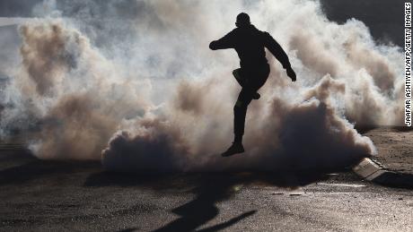 A protester jumps over smoke from burning tires during clashes with Israeli soldiers near the Hawara checkpoint, south of Nablus, on Friday.