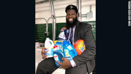 Cook holds an armful of donated laundry products. 