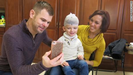 Christian and Nicole McDonald show Jadon photos on a phone while he gets measured for a new protective helmet.