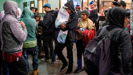 Asylum seekers stand at a bus stop after they were dropped off by ICE at the Greyhound bus station in downtown El Paso, Texas, late on December 23, 2018.