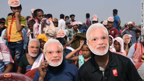 Supporters of the Bharatiya Janata Party (BJP) wearing masks of Indian Prime Minister Narendra Modi listen to Modi during an election rally at Phulbari in west Garo hills of Meghalaya on February 22, 2018.