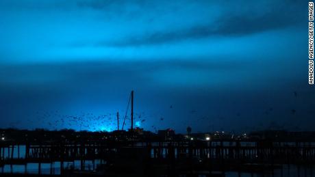 NEW YORK, USA - DECEMBER 27: Birds fly over a pier as a blue light illuminates the night sky after a transformer explosion at Queens Borough in New York, United States on December 27, 2018. (Photo by Simin Liu/Anadolu Agency/Getty Images)